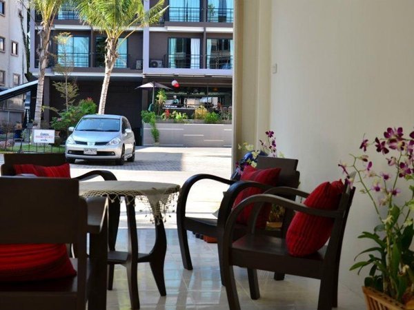 Chairs with red cushions in an open lounge facing the street at Admire House