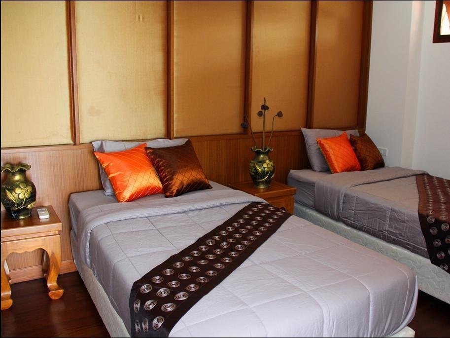 Two single beds with orange cushions inside Baan Nakaow Guest House