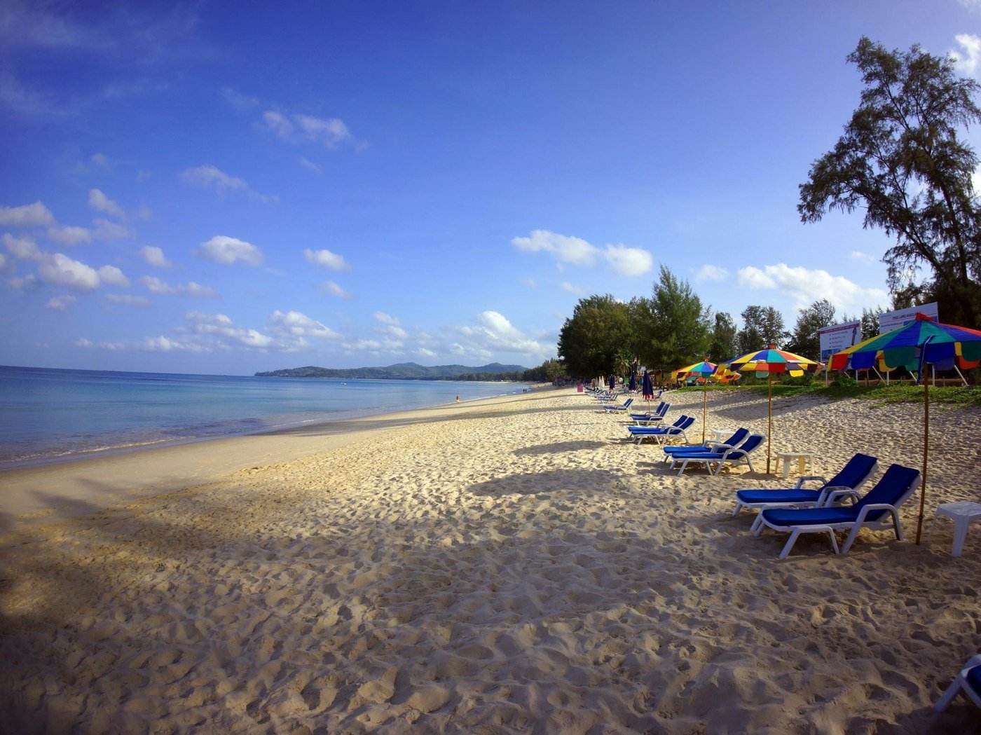 Sandy nearby beach with loungers and colourful umbrellas shown in the property listing