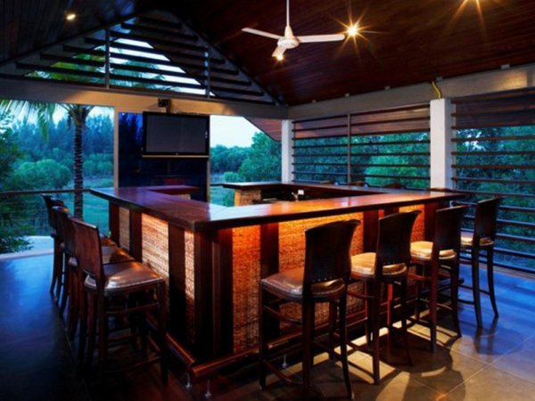 Covered bar counter with high stools and a television at Casuarina Shores