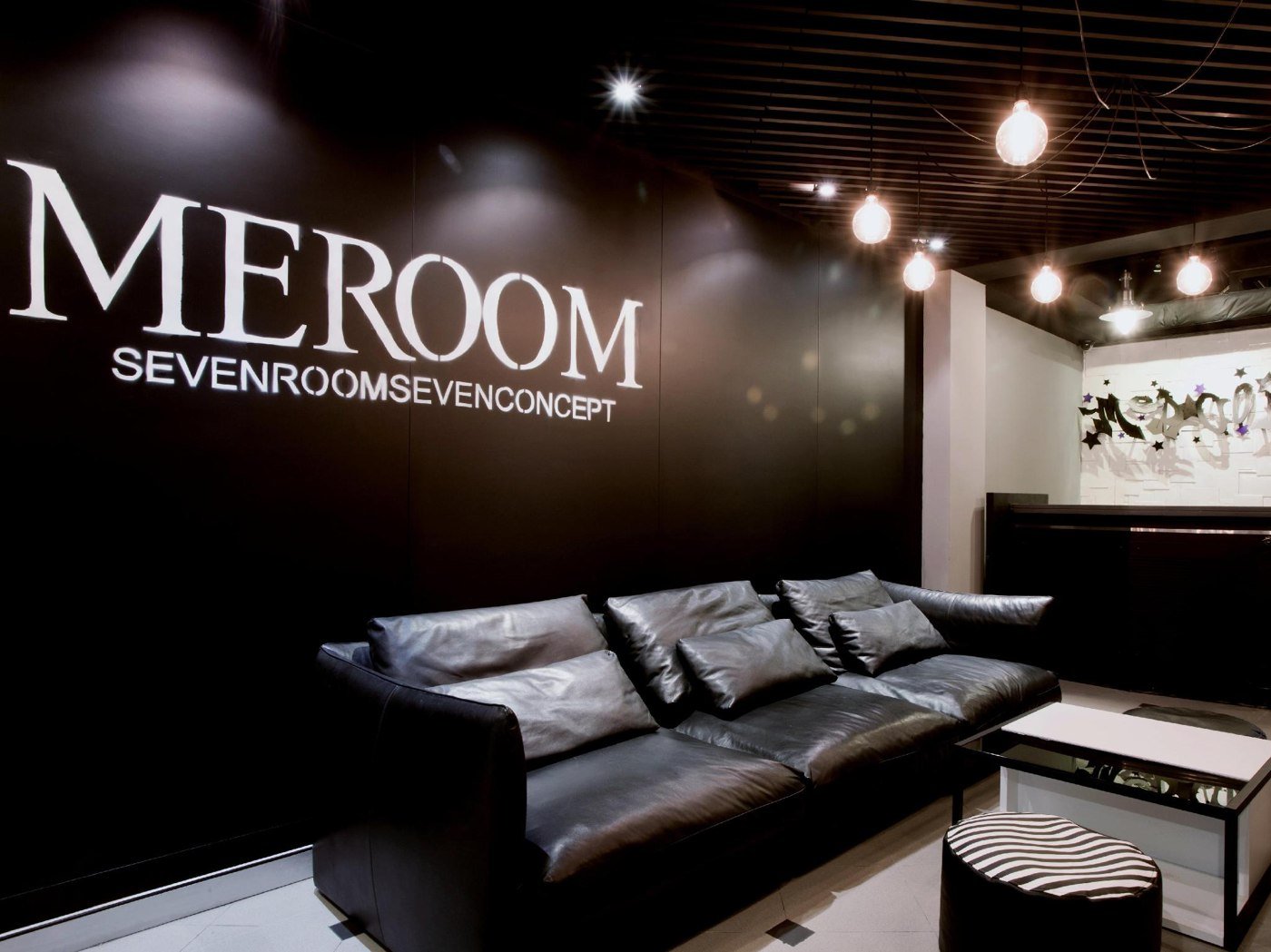 Sofa beneath the MEROOM Seven Rooms Seven Concept sign in the lobby
