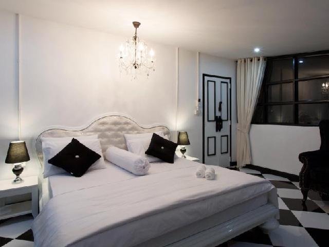 Black-and-white bedroom with a double bed, chandelier and checked floor