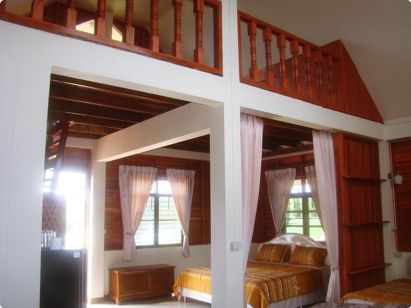 Bed beneath a wooden mezzanine inside accommodation at Petch Nakhonthai Homestay
