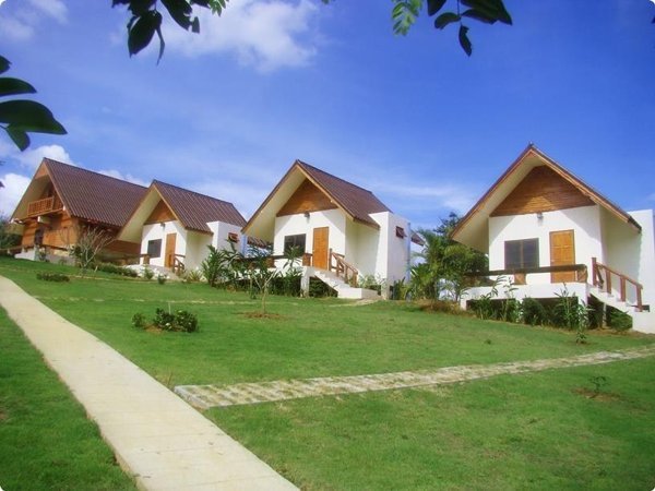 White cottages with pitched roofs beside a lawn and paved footpaths