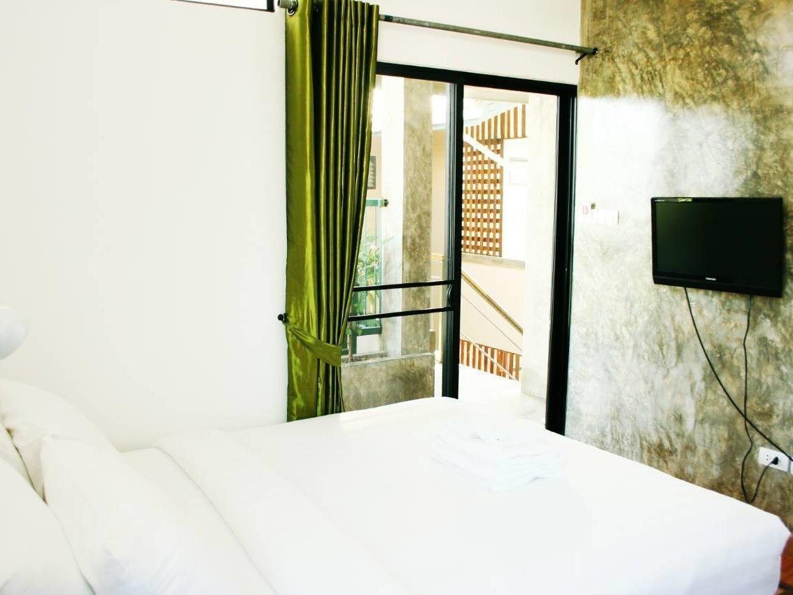 Double bedroom with green curtains, a wall-mounted television and glass balcony door