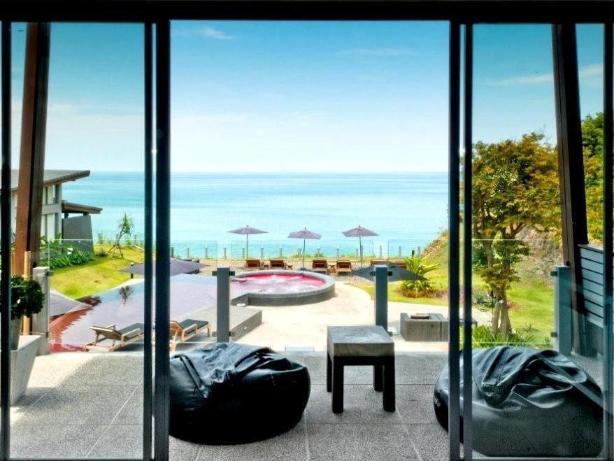 View through glass doors toward outdoor seating, the pool and sea at The Houben